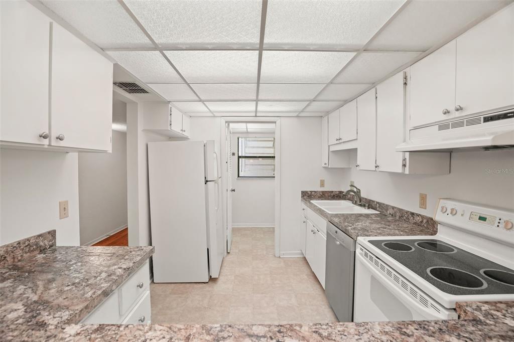 A kitchen features white cabinets, laminate countertops, a white refrigerator, and a drop ceiling — 1200 TARPON WOODS BOULEVARD UNIT L4, PALM HARBOR, FL