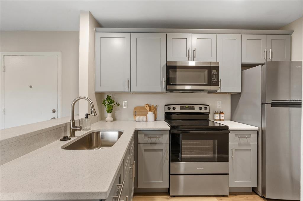 A kitchen features gray cabinets, stainless steel appliances, and light-colored countertops — 3848 N LAKE DRIVE UNIT 137, TAMPA, FL