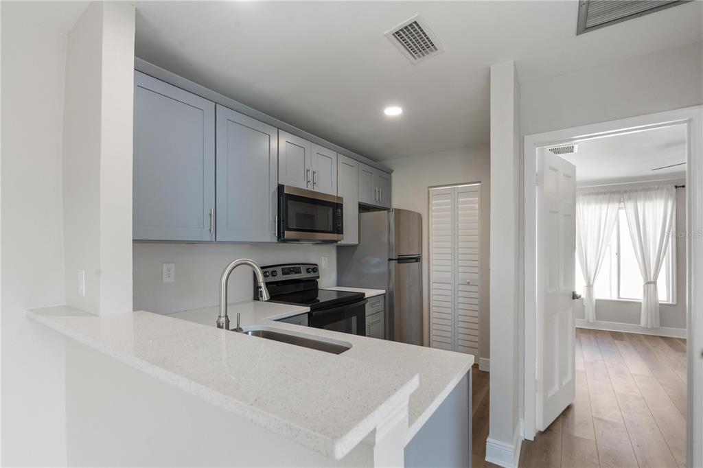 A kitchen features light blue cabinets, stainless steel appliances, and a white quartz countertop — 3848 N LAKE DRIVE UNIT 137, TAMPA, FL