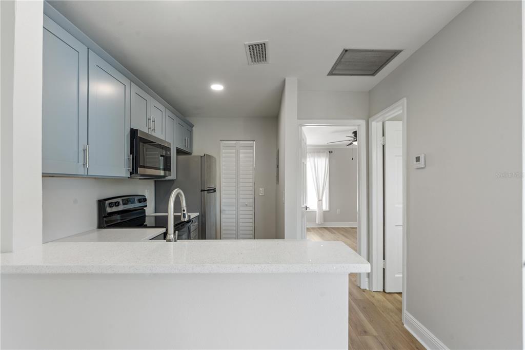 A kitchen with light blue cabinets, stainless steel appliances, and a white quartz breakfast bar — 3848 N LAKE DRIVE UNIT 137, TAMPA, FL