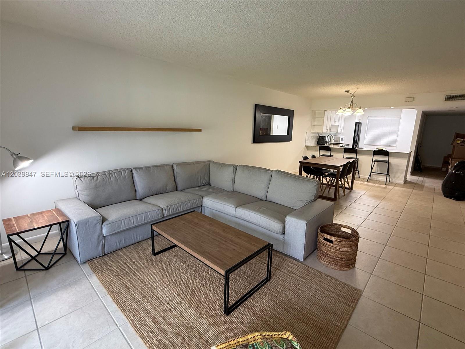 A living room with a gray sectional sofa, coffee table, and an adjacent dining area — WESTON, FL