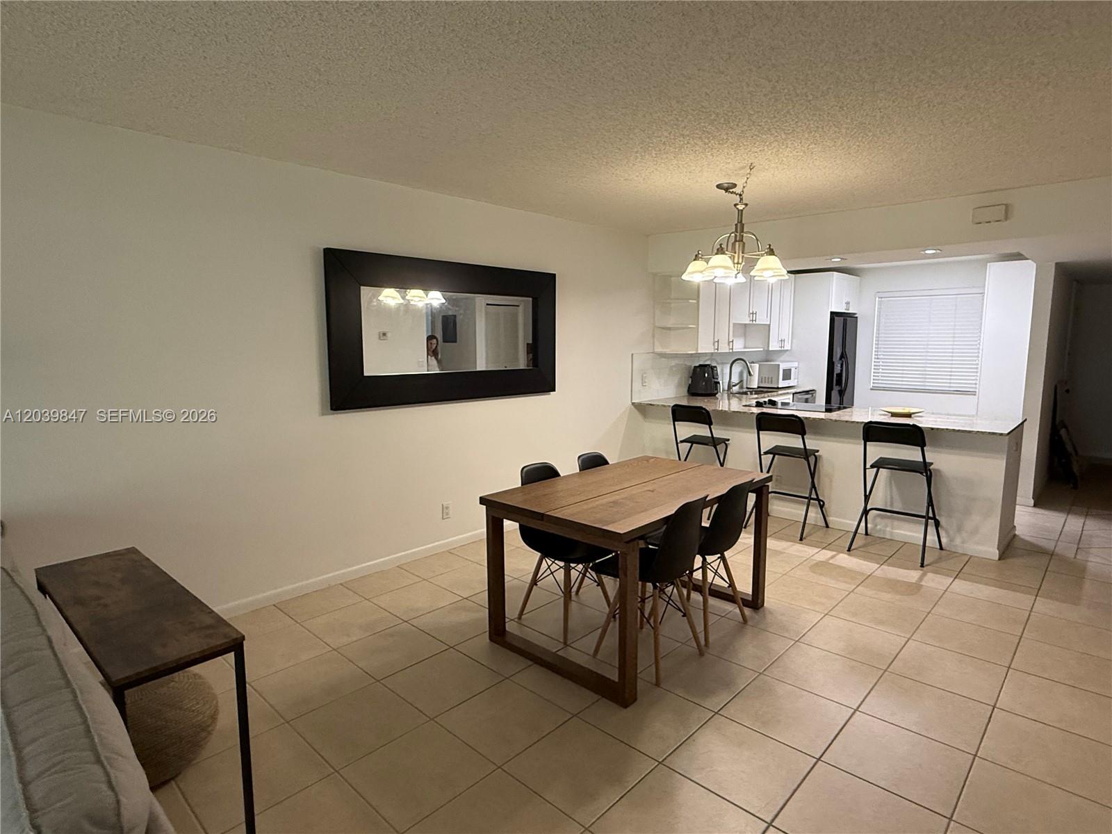 A dining area with a wooden table and chairs sits adjacent to an open kitchen — WESTON, FL