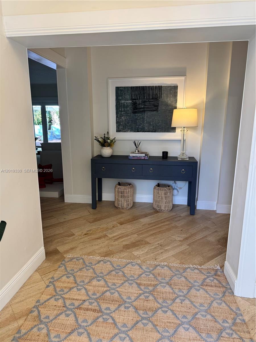 A dark console table with a lamp and artwork sits in a tiled entryway — 125 W Sunrise Ave, Coral Gables FL 33133, CORAL GABLES, FL