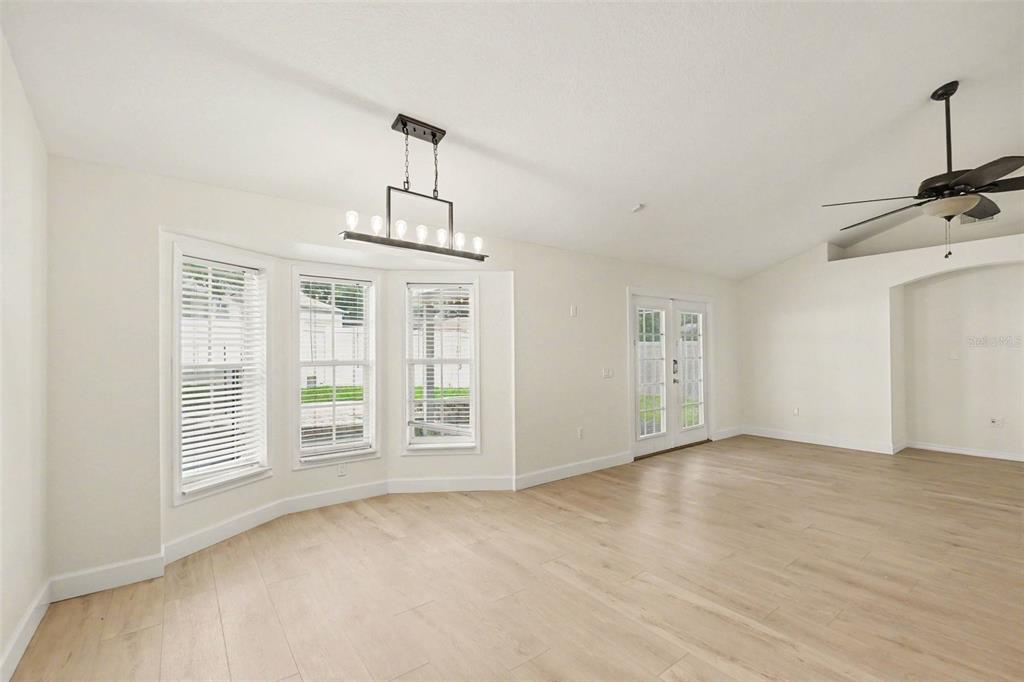 A bright dining area features light wood flooring, a modern chandelier, and a bay window — 7231 REMINGTON OAKS DRIVE, LAKELAND, FL