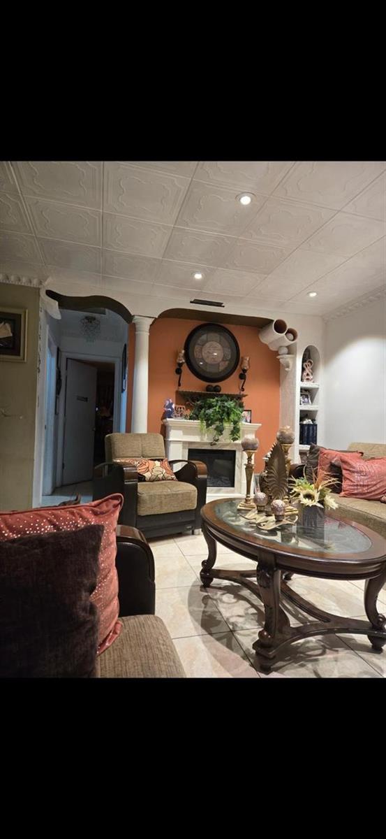 A living room features a fireplace, tiled floors, a coffered ceiling, and an arched entryway — 3200 NW 5th Terrace # 24, Pompano Beach FL 33064, POMPANO BEACH, FL