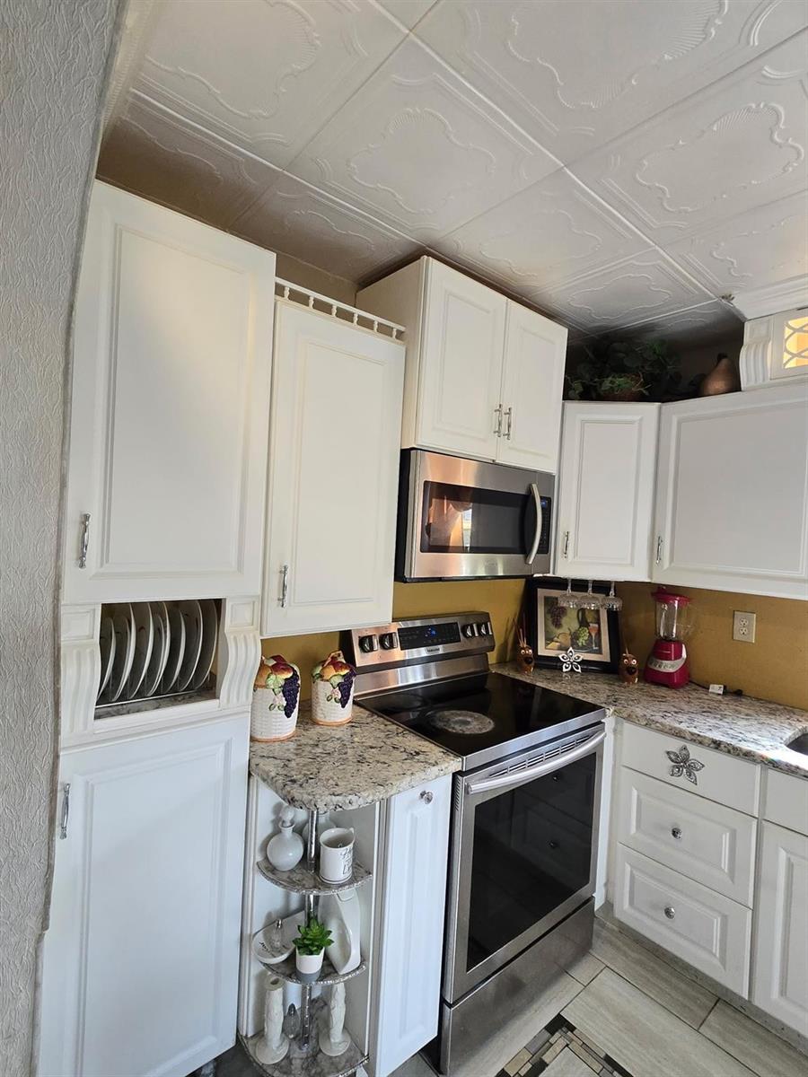A kitchen features white cabinets, stainless steel appliances, granite countertops, and a decorative ceiling — 3200 NW 5th Terrace # 24, Pompano Beach FL 33064, POMPANO BEACH, FL