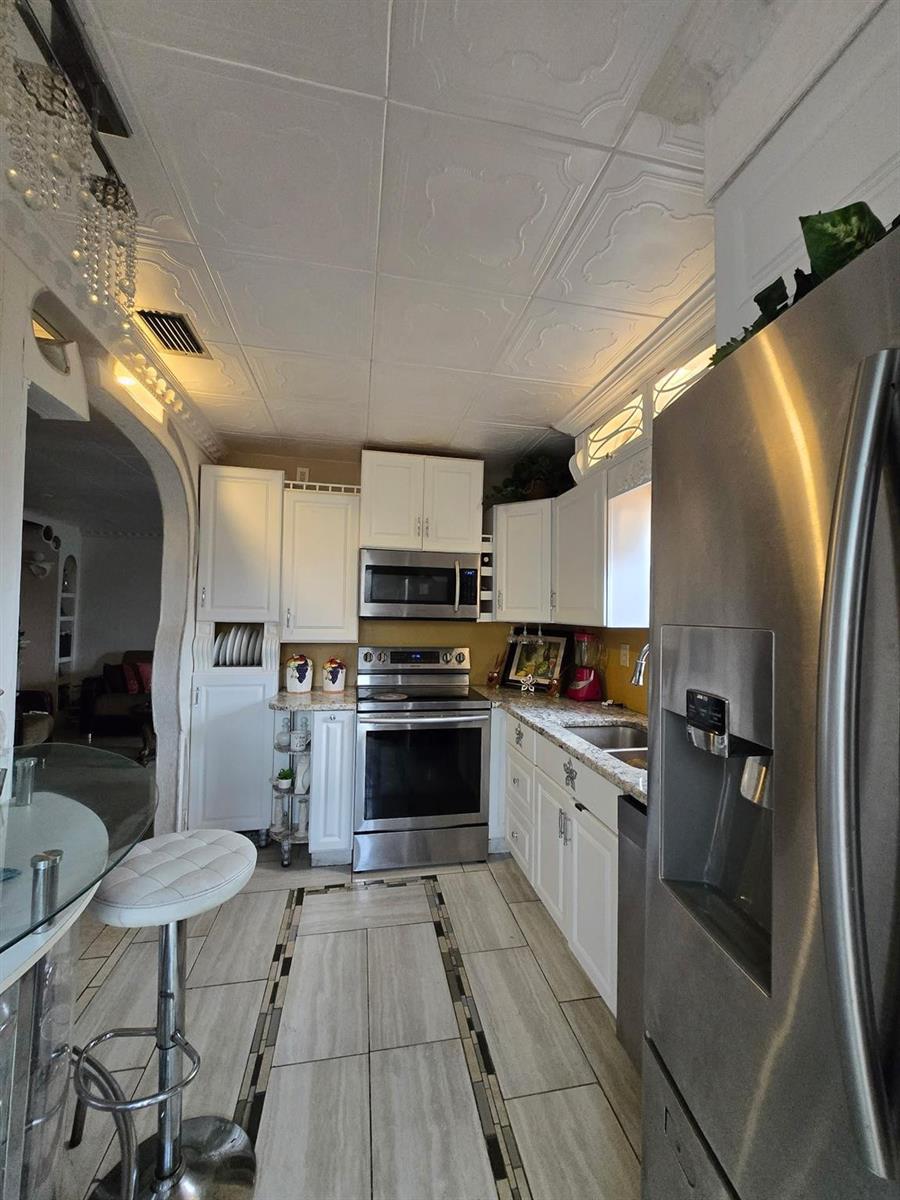 A kitchen features white cabinetry, stainless steel appliances, a tiled ceiling, and light-colored floor tiles — 3200 NW 5th Terrace # 24, Pompano Beach FL 33064, POMPANO BEACH, FL