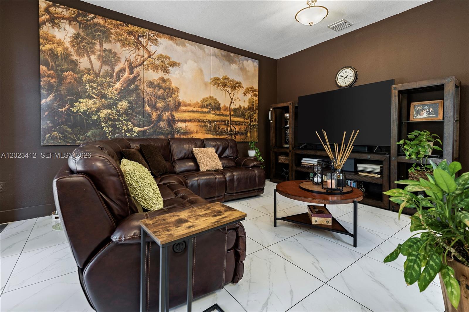 A living room features a large landscape mural, brown leather sectional, and white tiled floors — 12704 SW 131st Ter, Miami FL 33186, MIAMI, FL