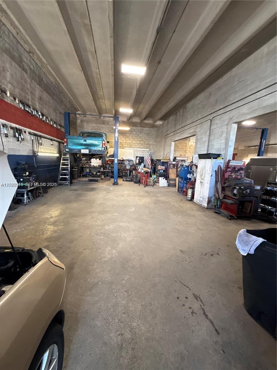 This auto repair shop features a concrete floor, exposed ceiling beams, and a vehicle lift — 1750 W 41st St, Hialeah FL 33012, HIALEAH, FL