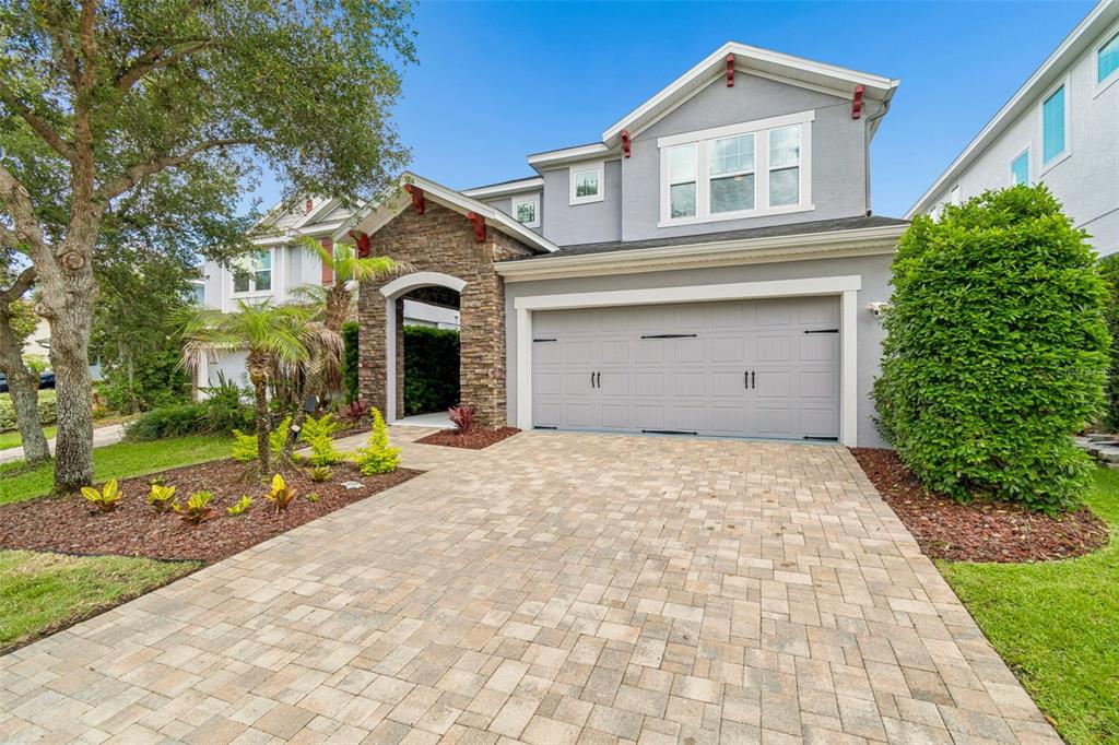 A two-story house with a stone-accented entryway, gray siding, and a paved driveway — 16214 BAYBERRY VIEW DRIVE, LITHIA, FL