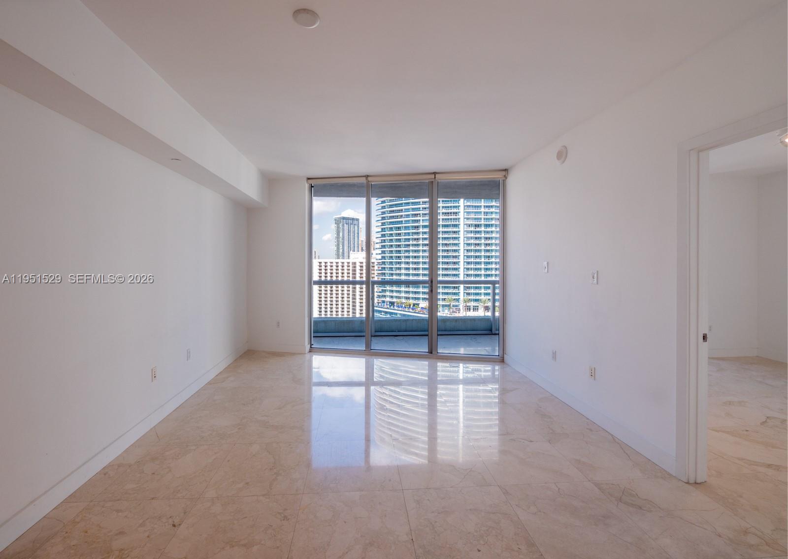 An empty living room features white walls, marble tile flooring, and floor-to-ceiling windows — 465 Brickell Ave # 2304, Miami FL 33131, MIAMI, FL