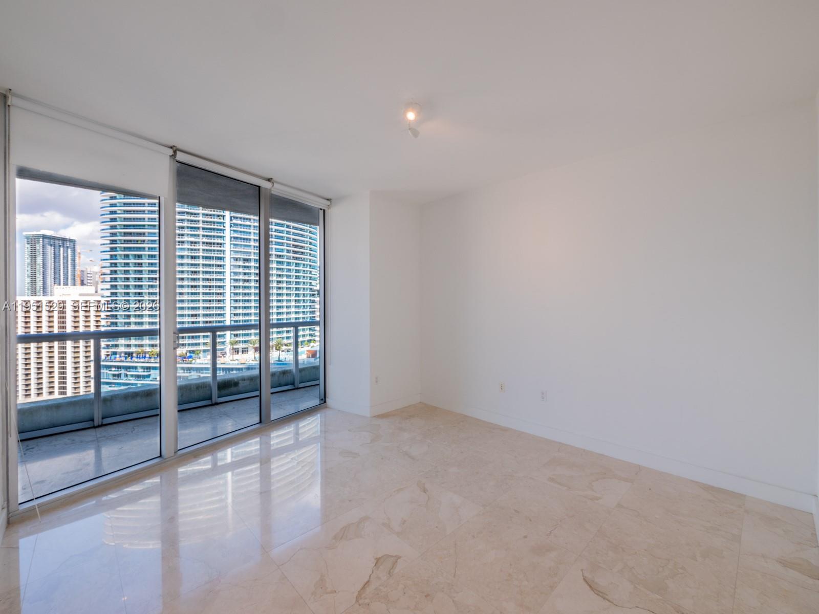 An empty room with marble floors, white walls, and floor-to-ceiling windows overlooking city buildings — 465 Brickell Ave # 2304, Miami FL 33131, MIAMI, FL