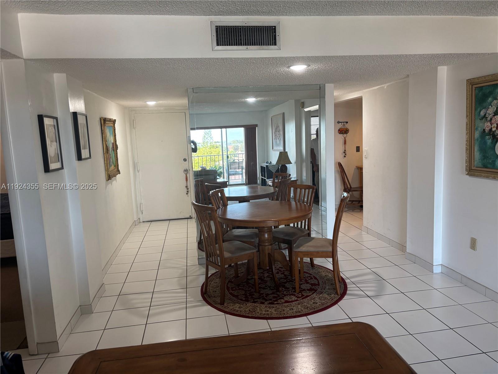 A dining area features a round wooden table, chairs, and a large mirrored wall — 14250 SW 62nd St # 520, Miami FL 33183, MIAMI, FL