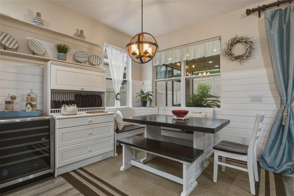 A dining nook features a farmhouse-style table, bench seating, white shiplap walls, and a chandelier — 16742 ABBEY HILL COURT, CLERMONT, FL