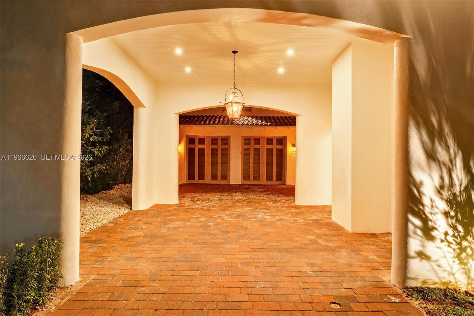 A covered brick driveway leads to a garage with two sets of wooden doors — 1514 Consolata Ave, Coral Gables FL 33146, CORAL GABLES, FL
