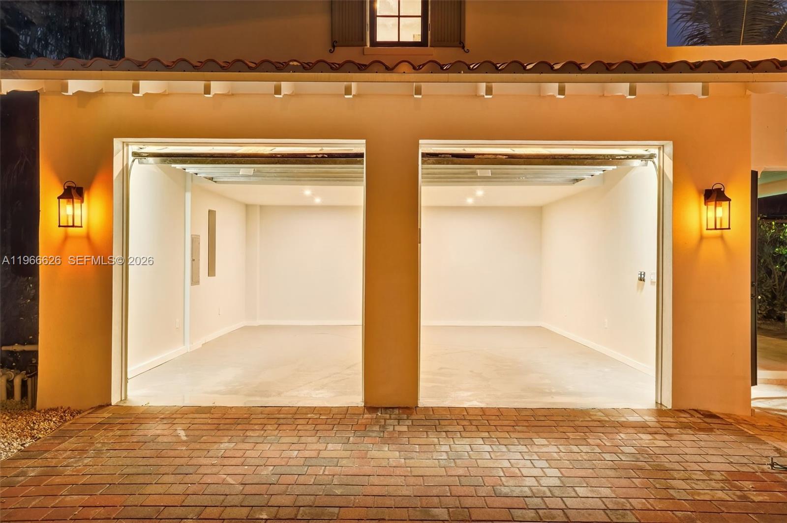 An empty two-car garage with a brick driveway and exterior wall-mounted lanterns — 1514 Consolata Ave, Coral Gables FL 33146, CORAL GABLES, FL