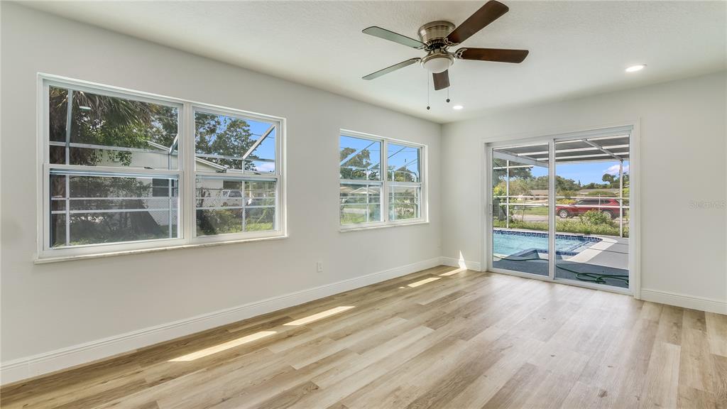 An empty room with light wood-look flooring, a ceiling fan, and sliding doors to a pool — 4294 NIMONS STREET, ORLANDO, FL