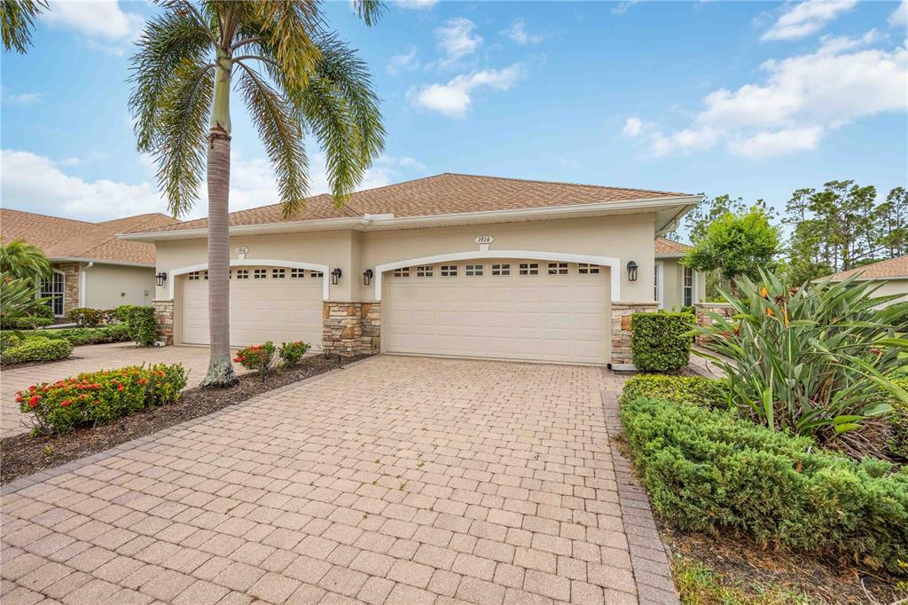 A beige house with a two-car garage and a paved driveway under a blue sky — 1914 SCARLETT AVENUE, NORTH PORT, FL