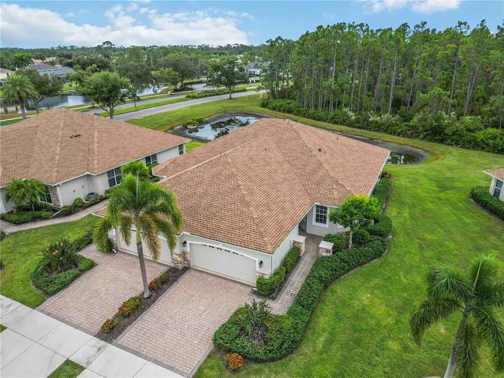 An aerial view of a suburban house with a tan roof, garage, and landscaped yard — 1914 SCARLETT AVENUE, NORTH PORT, FL