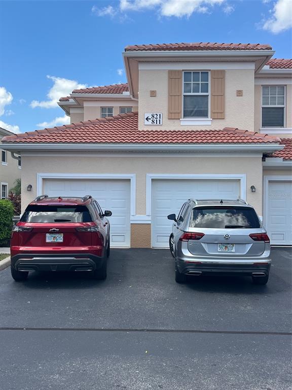 Two cars are parked in front of a two-story residential building with two garage doors — 240 W END DRIVE UNIT 821, PUNTA GORDA, FL