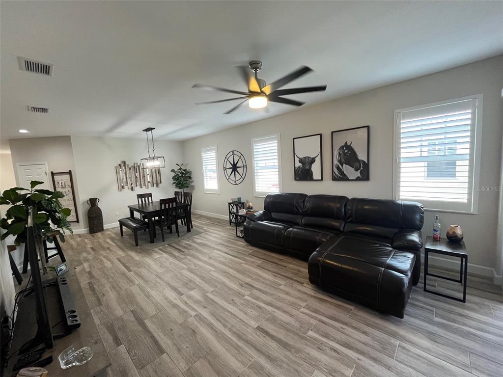 A living and dining room features wood-look tile flooring, a leather sectional, and a ceiling fan — 240 W END DRIVE UNIT 821, PUNTA GORDA, FL