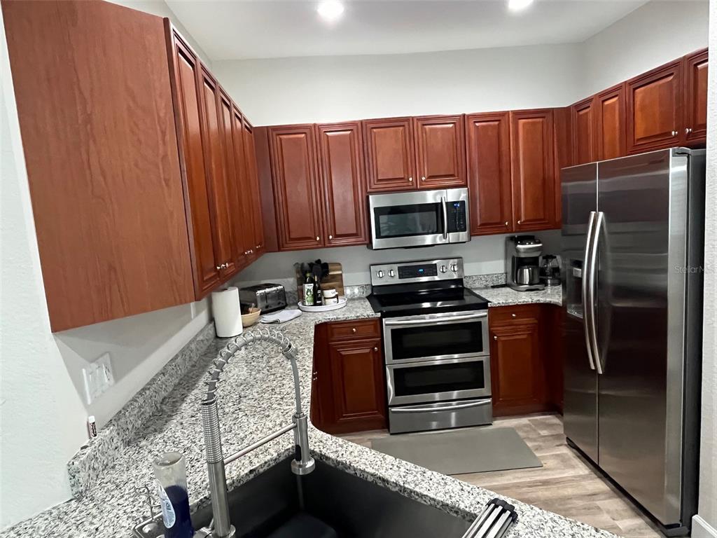 A kitchen features cherry wood cabinets, granite countertops, and stainless steel appliances — 240 W END DRIVE UNIT 821, PUNTA GORDA, FL