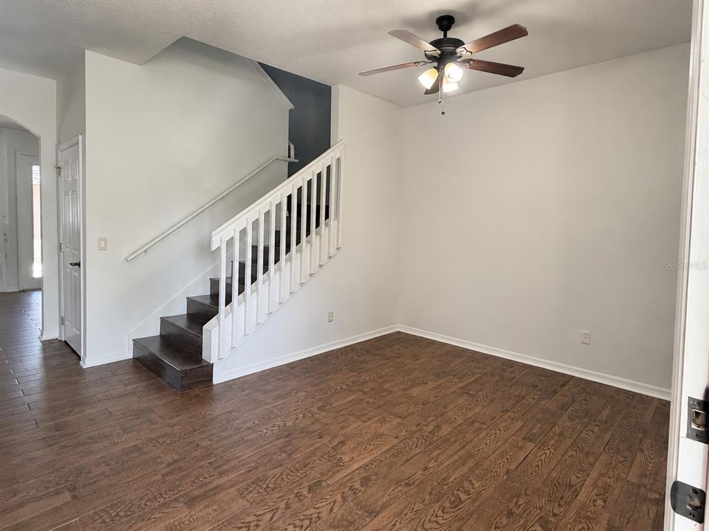 A room with wood-look flooring, a white staircase with dark treads, and a ceiling fan — 4907 TERRAPIN BOULEVARD, ST CLOUD, FL