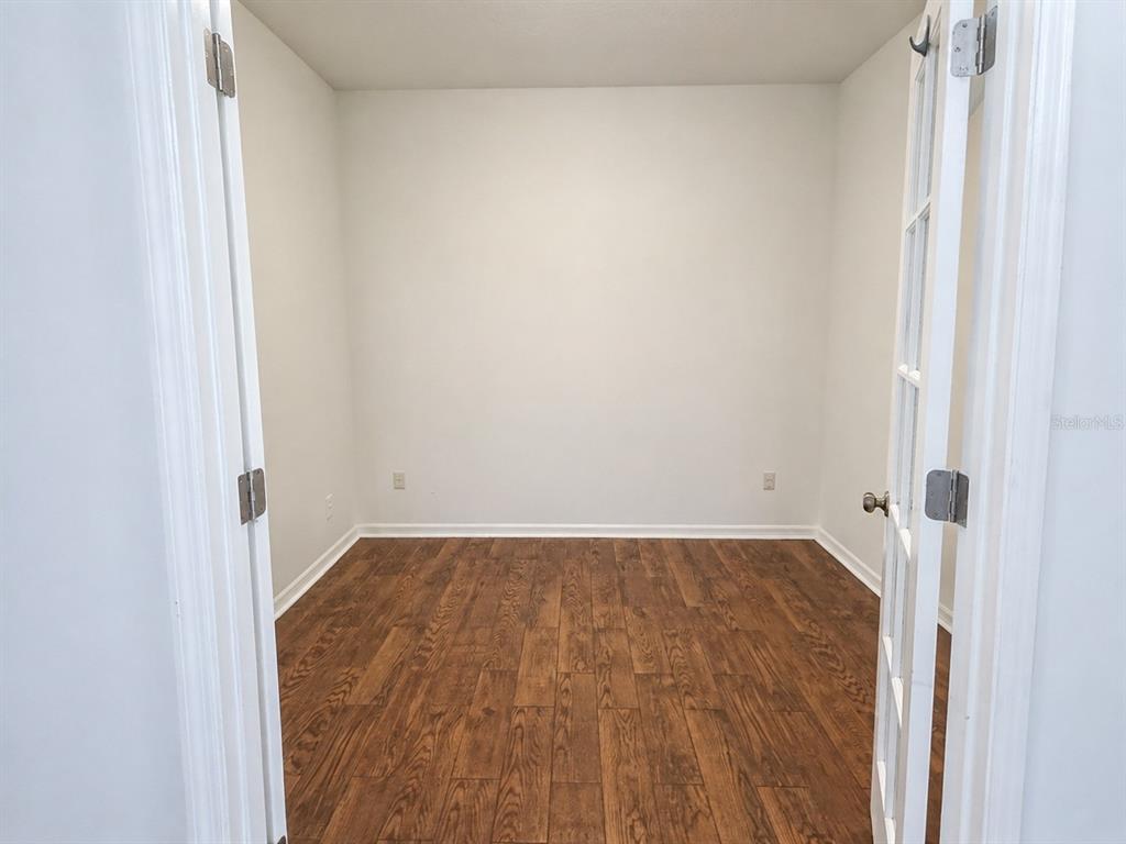An empty room with wood-look flooring and French doors — 4907 TERRAPIN BOULEVARD, ST CLOUD, FL