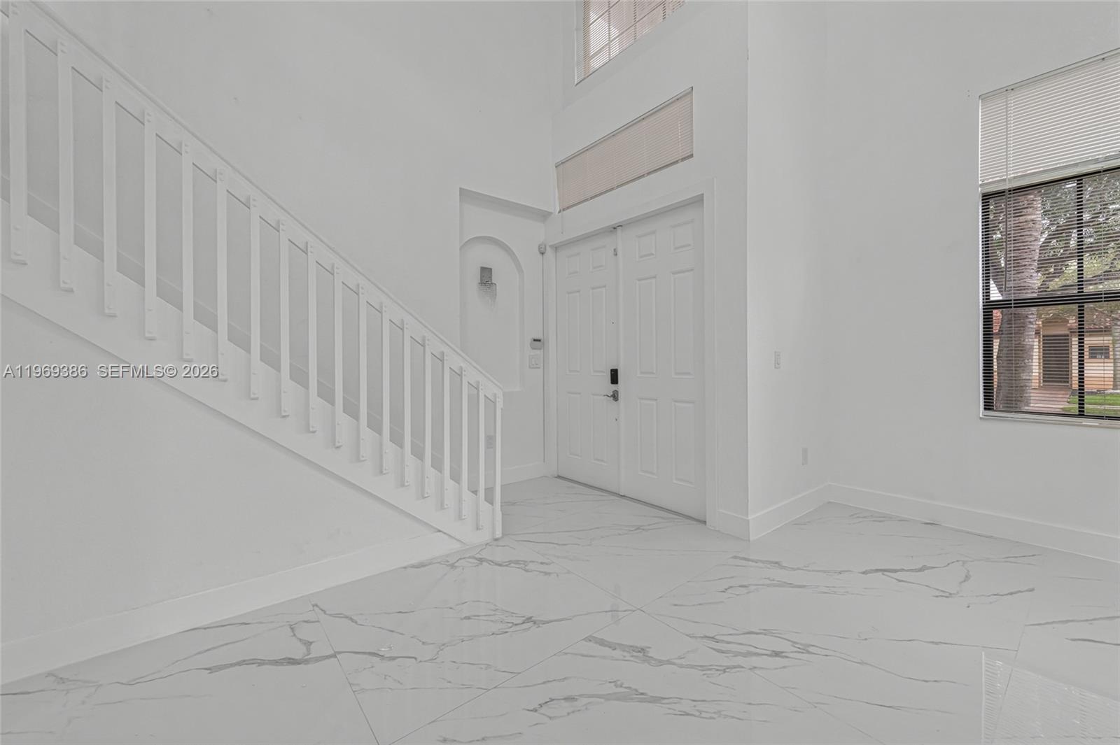 An entryway features white marble-look tile flooring, a white staircase, and double front doors — 642 SE 37th PL, Homestead FL 33033, HOMESTEAD, FL