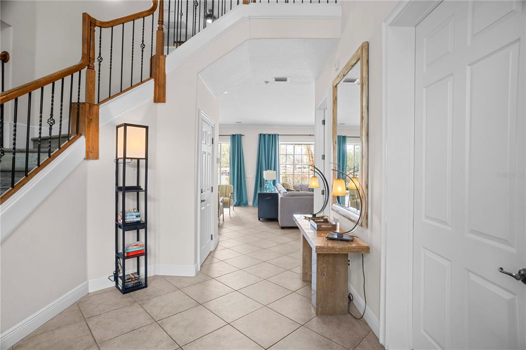 A bright foyer features tile flooring, a staircase with iron railings, and a console table — 7388 GATHERING COURT, REUNION, FL