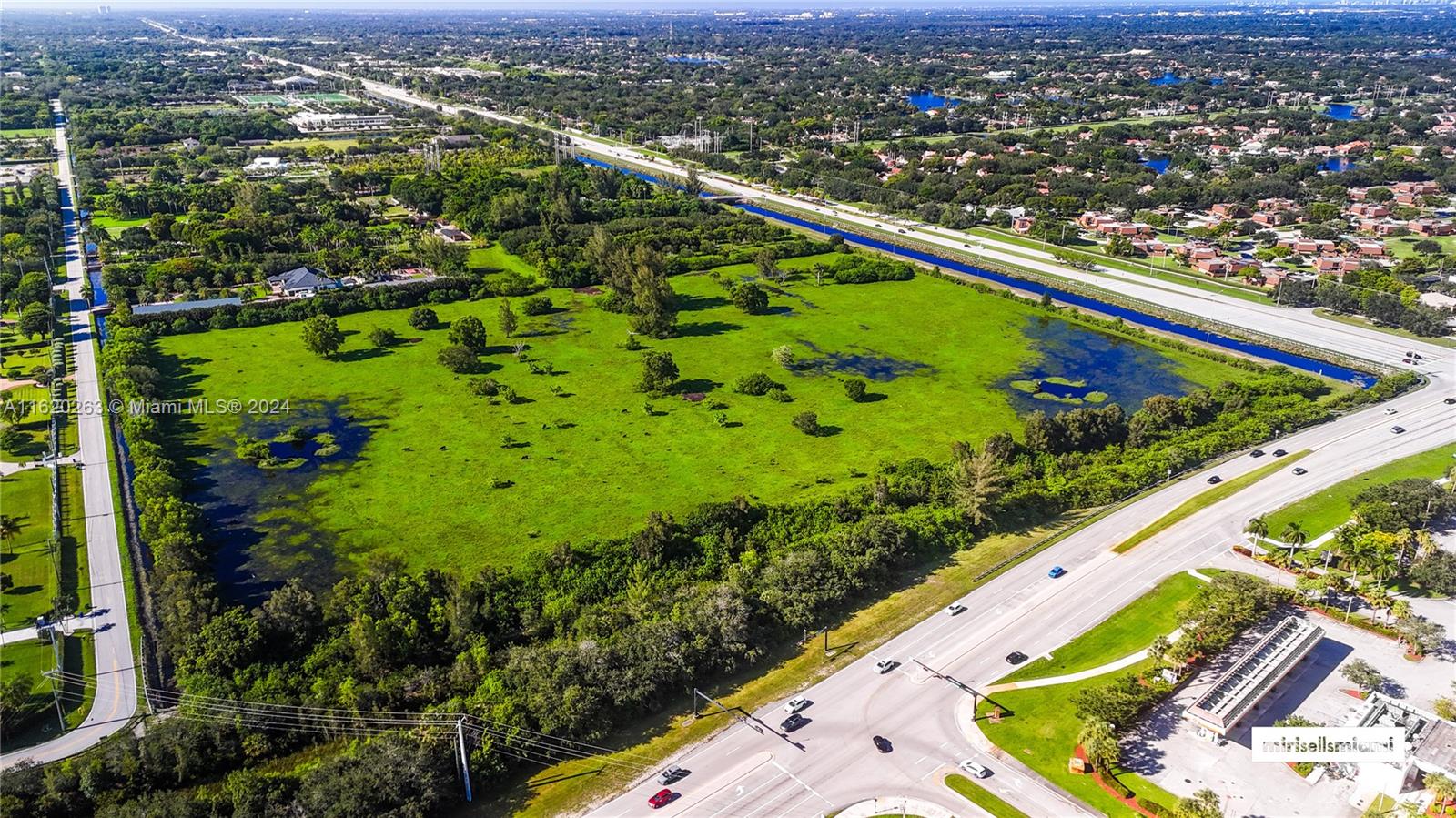 An aerial view shows a large, grassy, partially flooded lot bordered by roads and canals — 6701 SW 124th Ave, Southwest Ranches FL 33330, SOUTHWEST RANCHES, FL