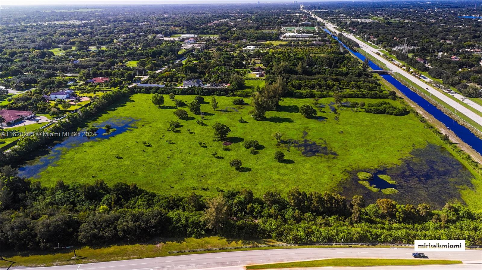 An aerial view shows a large, grassy, partially flooded lot bordered by a road and canal — 6701 SW 124th Ave, Southwest Ranches FL 33330, SOUTHWEST RANCHES, FL