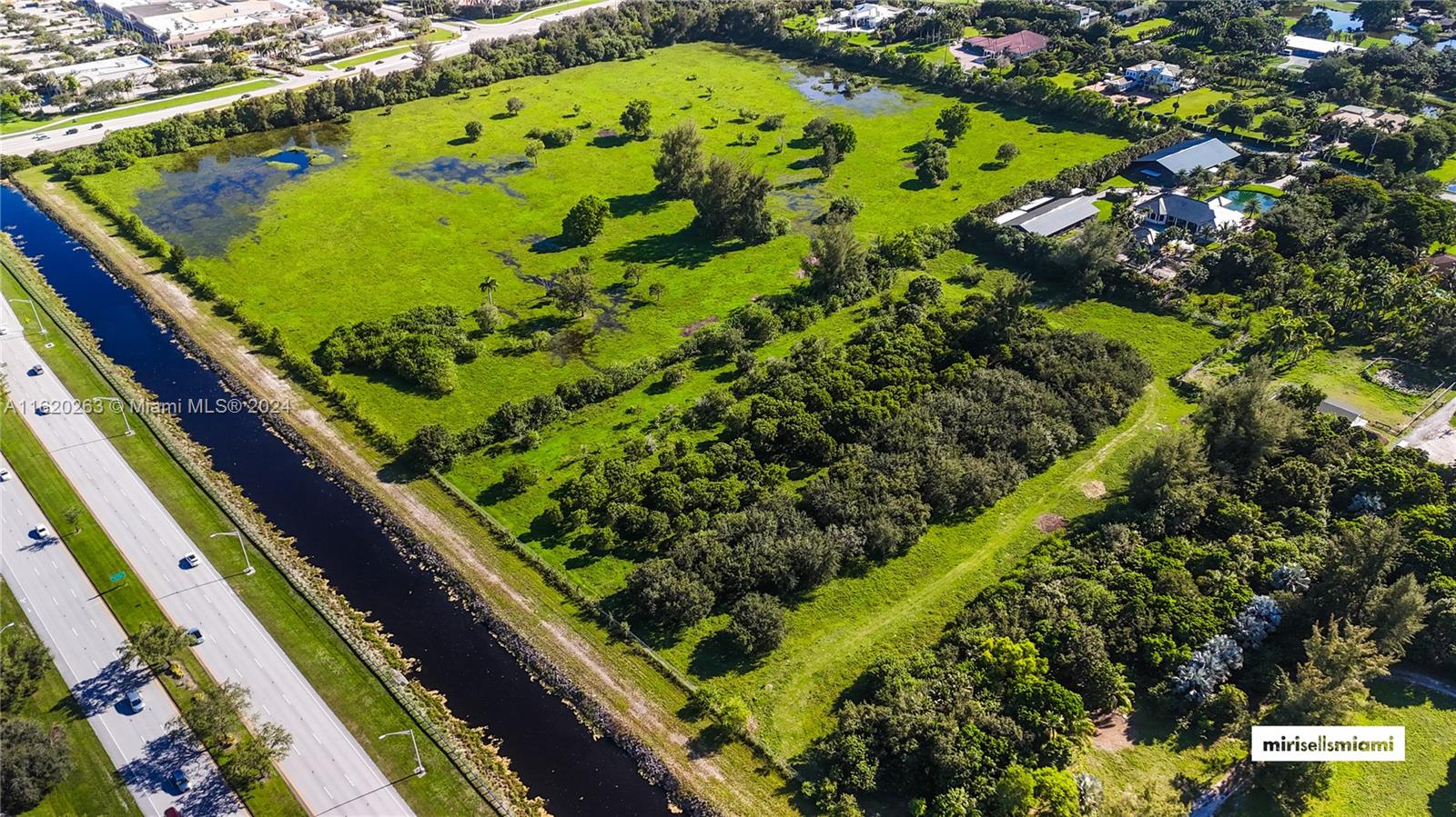 An aerial view shows a large, grassy lot with scattered trees and a bordering canal — 6701 SW 124th Ave, Southwest Ranches FL 33330, SOUTHWEST RANCHES, FL