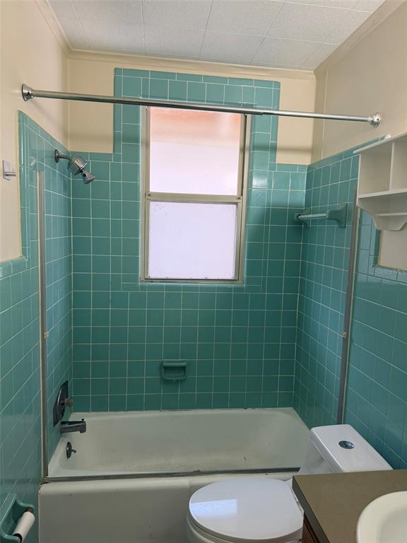 A bathroom features a white bathtub and toilet surrounded by vintage turquoise square wall tiles — 639 E AMELIA STREET, ORLANDO, FL