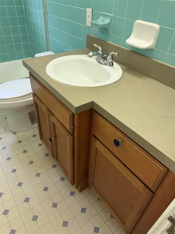 A bathroom features a wooden vanity with a white sink, beige countertop, and blue tiles — 639 E AMELIA STREET, ORLANDO, FL