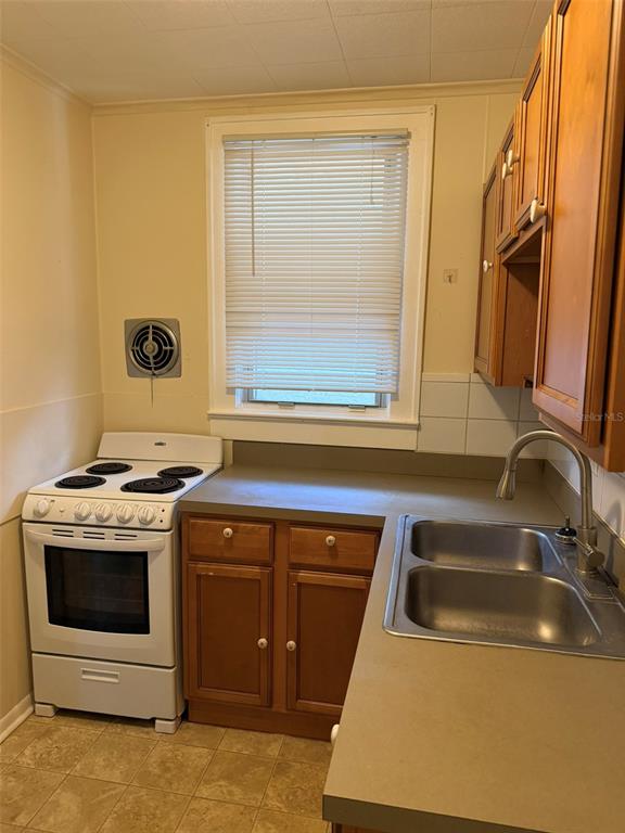 A kitchen features a white electric stove, a double-basin sink, and wooden cabinets — 639 E AMELIA STREET, ORLANDO, FL