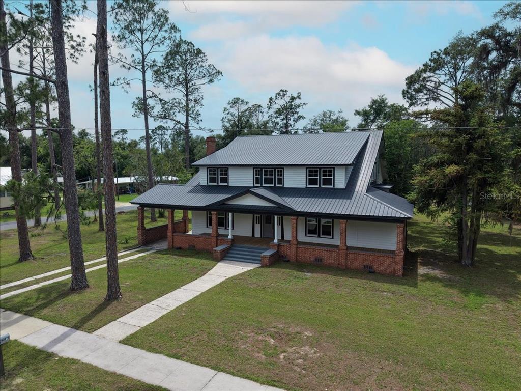 A two-story house with a metal roof, white siding, and a brick porch foundation — 1103 N JEFFERSON STREET, PERRY, FL