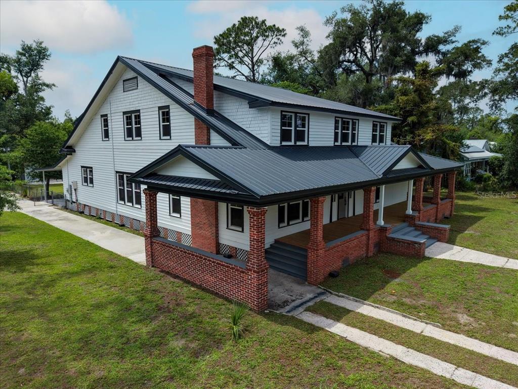 An aerial view of a white two-story house with a metal roof and brick porch — 1103 N JEFFERSON STREET, PERRY, FL