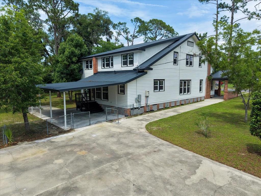 A two-story white house with a metal roof, a covered patio, and a concrete driveway — 1103 N JEFFERSON STREET, PERRY, FL