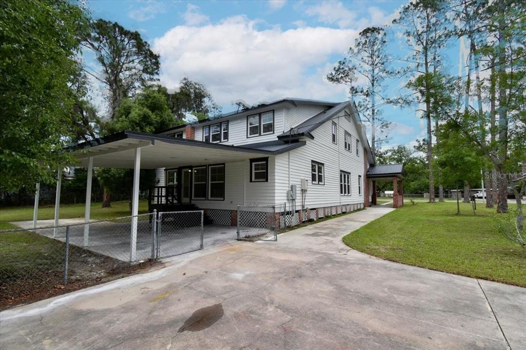 The exterior of a two-story white house with a metal roof and a side carport — 1103 N JEFFERSON STREET, PERRY, FL