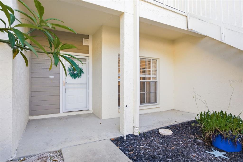 A detached garage with a white door and beige siding sits next to a driveway — 11510 SHIPWATCH DRIVE UNIT 1372, LARGO, FL