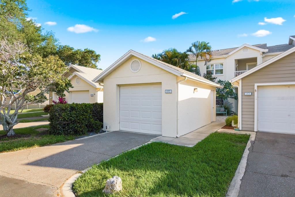 A light blue bench sits on a gravel courtyard in front of a white building — 11510 SHIPWATCH DRIVE UNIT 1372, LARGO, FL