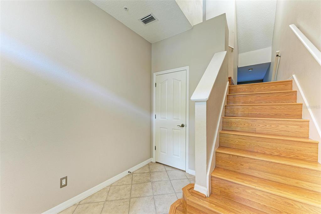 An entryway features a tiled floor, a white door, and wooden stairs leading upward — 3047 POINTEVIEW DRIVE, TAMPA, FL