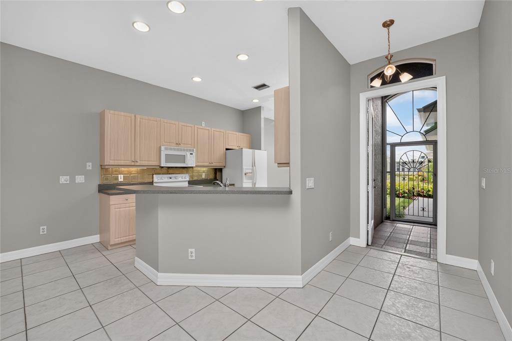 A kitchen with light wood cabinets and a breakfast bar overlooks a tiled dining area — 1611 ATARES DRIVE Unit 111, PUNTA GORDA, FL
