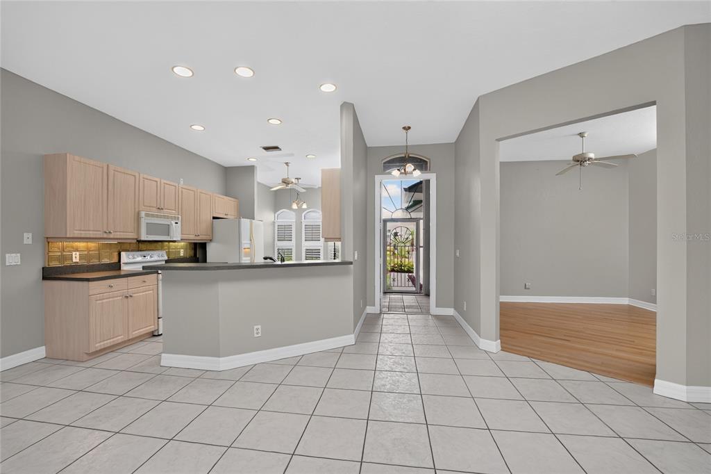 A kitchen with light wood cabinets and tile flooring opens to a dining area — 1611 ATARES DRIVE Unit 111, PUNTA GORDA, FL