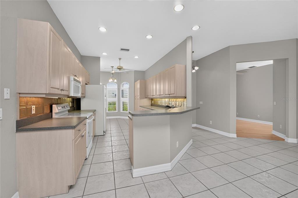A kitchen with light wood cabinets, gray countertops, tile flooring, and a breakfast bar — 1611 ATARES DRIVE Unit 111, PUNTA GORDA, FL