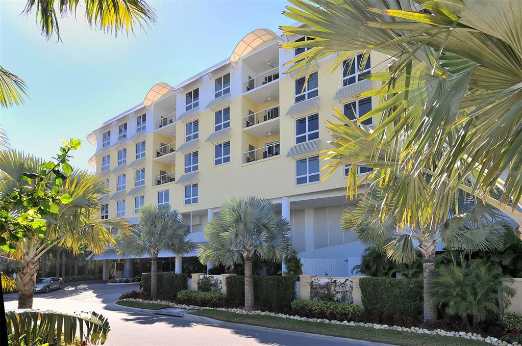 A multi-story yellow apartment building with balconies is surrounded by palm trees and landscaping — 915 SEASIDE DRIVE UNIT 504, Weeks 6-7, SARASOTA, FL