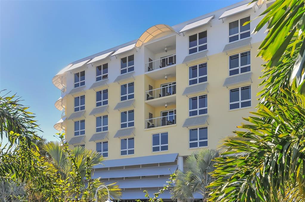 A multi-story building with yellow stucco walls, recessed balconies, and louvered window awnings — 915 SEASIDE DRIVE UNIT 504, Weeks 6-7, SARASOTA, FL