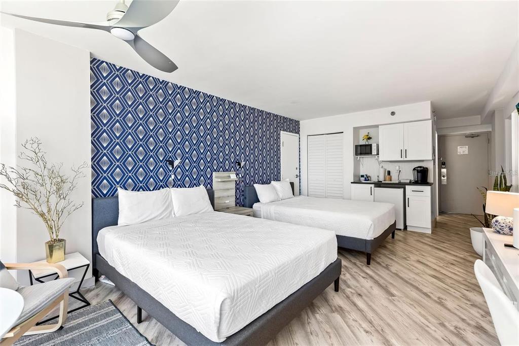 A hotel room features two beds, a kitchenette, and a blue geometric accent wall — 1909 S ATLANTIC AVENUE UNIT 411 & 412, DAYTONA BEACH, FL