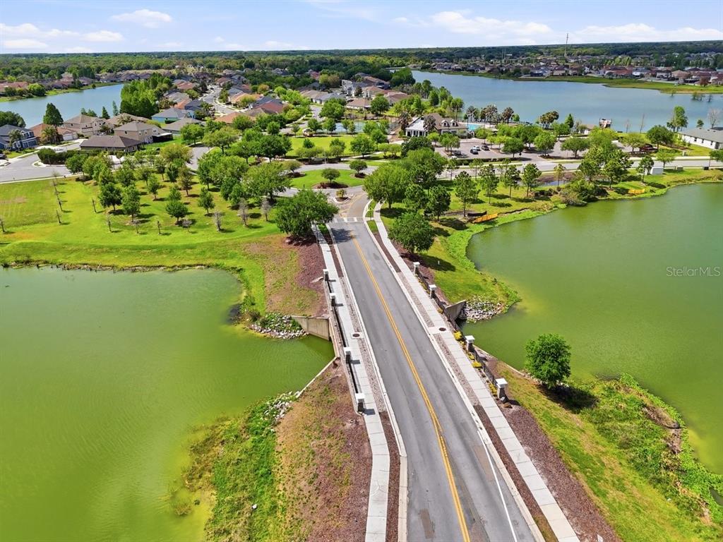 An aerial view shows a road crossing a bridge over a lake in a neighborhood — 6431 COMO PLACE, LAKELAND, FL